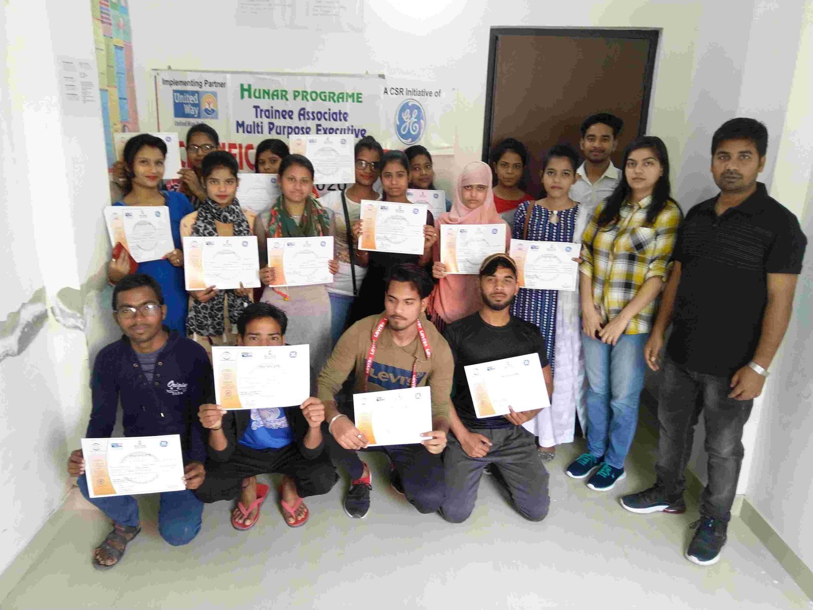 A group of young Hunar participants and team members holding course certificates.