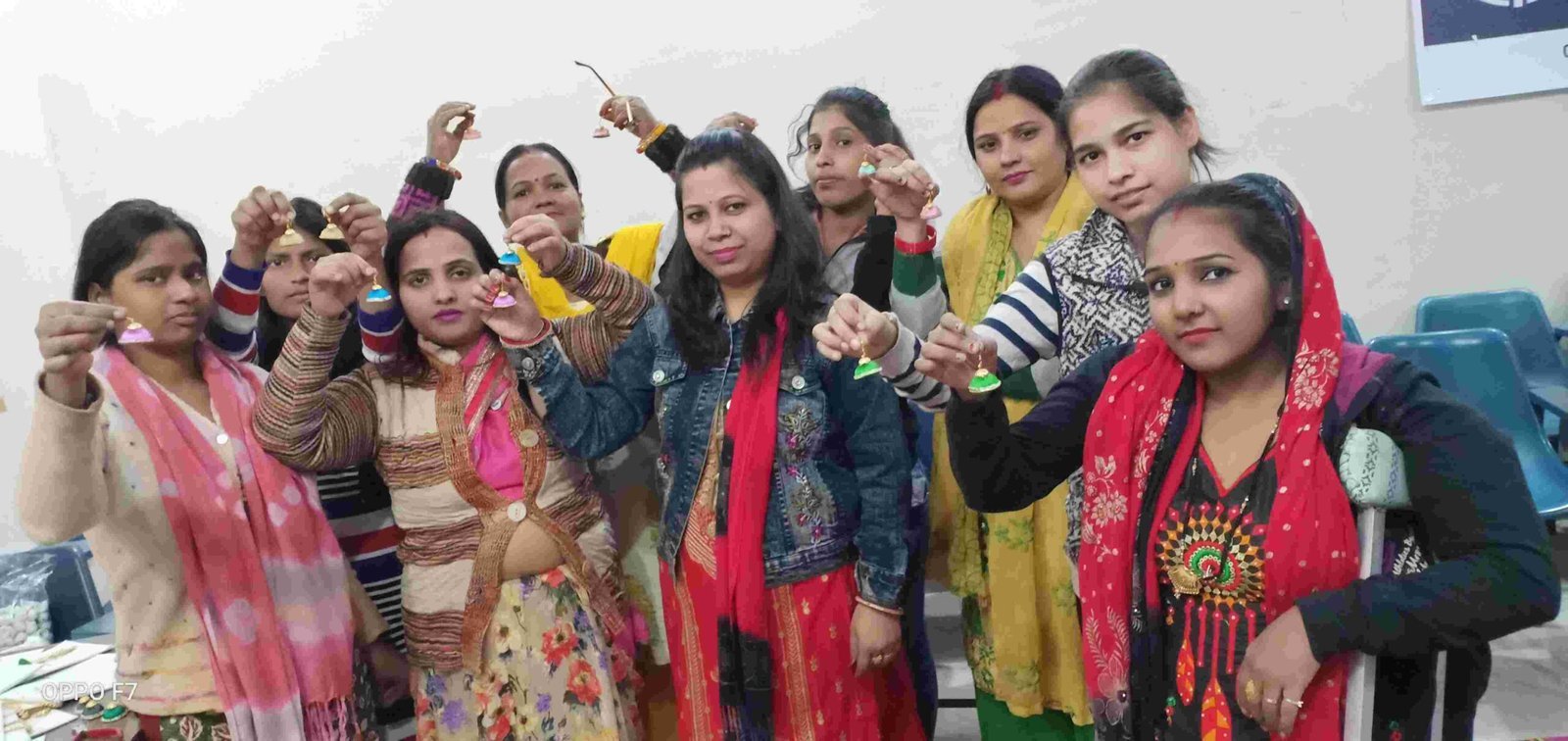 Women standing together and holding small colourful handmade jewellery pieces.